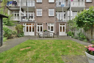 Amsterdam, Netherlands - 10 April, 2021: a brick building on the side of a street with cars parked in front and trees lining the sidewalk behind it