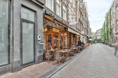a street with tables and chairs in front of a storefront on a bricked sidewalk next to some buildings