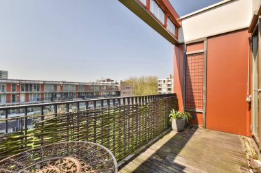 Sol tarafında sandalyeler ve parmaklıklar olan bir balkon, üst güverteden şehre bakıyor.