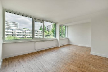 boş bir oda ahşap zeminli ve büyük pencereli şehir manzarasına bakan