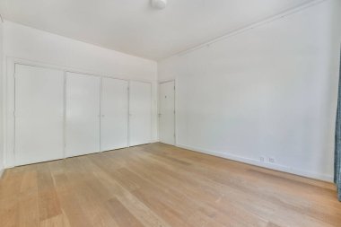 Beyaz duvarları ve ahşap döşemeleri olan boş bir oda tavandan sarkan mavi bir perde var.