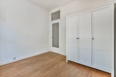 Ahşap zeminleri ve beyaz kapıları olan boş bir oda. Odada olacak kimse yok.