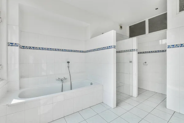壁に青と白のタイルのバスルーム 部屋の真ん中にシャワーストールとバスタブ — ストック写真