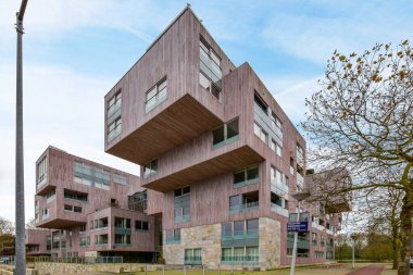 Bir caddenin ortasında sıra dışı görünümlü bir bina. Arabalar yan tarafta ve insanlar etrafında yürüyor.