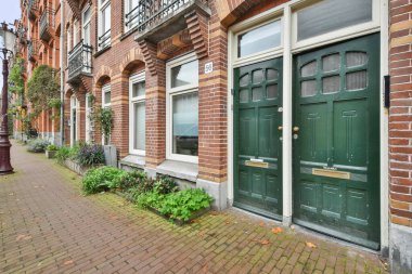 Amsterdam, Netherlands - 10 April, 2021: a brick building on the side of a street with cars parked in front and trees lining the sidewalk behind it