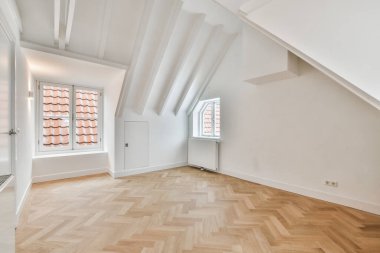 Odanın ortasında ahşap döşemeli ve beyaz duvarlı boş bir oda dışarıya bakan bir penceredir.