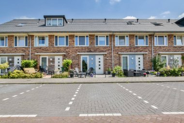 Önünde iki garaj, arkasında bir tane de mavi gökyüzü olan tuğladan bir ev.