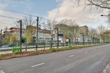 Amsterdam, Hollanda - 10 Nisan 2021: Arabası ve yolu olmayan boş bir cadde ve arka plandaki bazı binalar çıplak ağaçlardır.