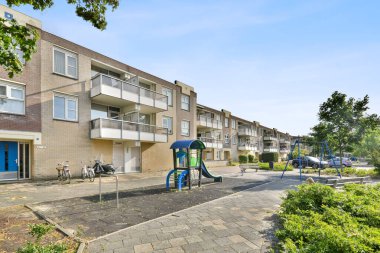 Amsterdam, Hollanda - 10 Nisan 2021: Parkta bir oyun alanı. Yerde yapraklar ve yanında ağaçlar, yukarıda mavi gökyüzü.