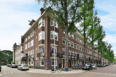 Amsterdam, Hollanda - 10 Nisan 2021: Önünde bisikletleri olan bir apartman ve yol kenarında ağaçlar olan bir apartman.