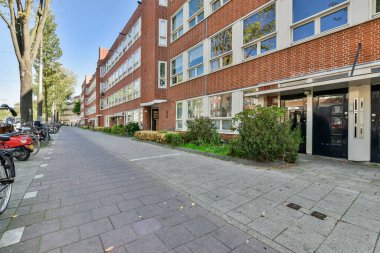 Amsterdam, Hollanda - 10 Nisan 2021: kaldırımlara parketmiş bisikletli bir şehir sokağı ve arka planda binalar, hepsi pencerelerine tuğla örülmüş.