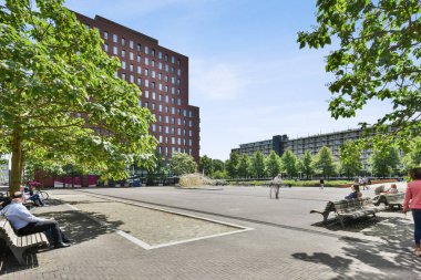 Amsterdam, Netherlands - 10 April, 2021: a building in the middle of an urban area with cars parked on the street and people walking down the sidewalk