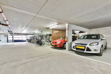 Amsterdam, Hollanda - 10 Nisan 2021: Bir otoparka park edilmiş bisiklet ve bisiklet parkının arkasındaki duvara yapışmış bir araba