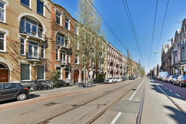 stock image a city street with cars parked on the side and people walking down the road in the distance to the right