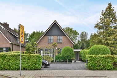 Amsterdam, Hollanda - 10 Nisan 2021: sokağın her iki tarafında da ağaçlar ve çalılar olan bir evin ortasında bir tabela var.