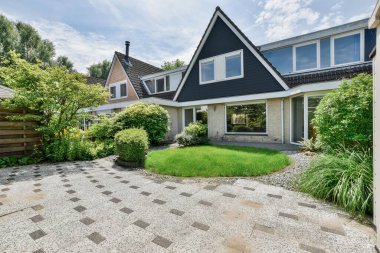 Amsterdam, Hollanda - 10 Nisan 2021: Çimlerin ve çalıların ortasında, sağında bahçe alanı olan bir ev