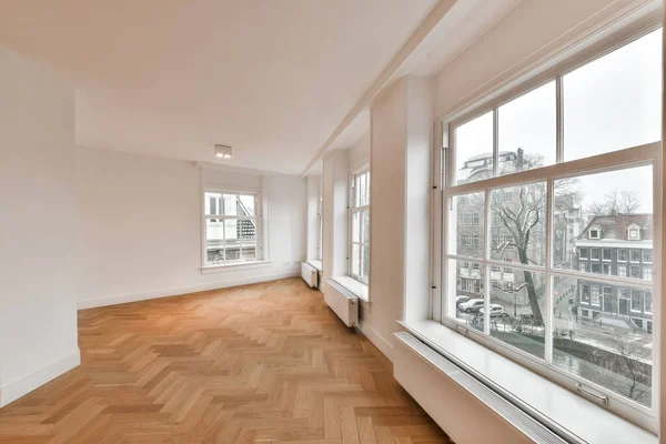 木製の床と大きな窓のある空の部屋が街の風景を眺めながら — ストック写真