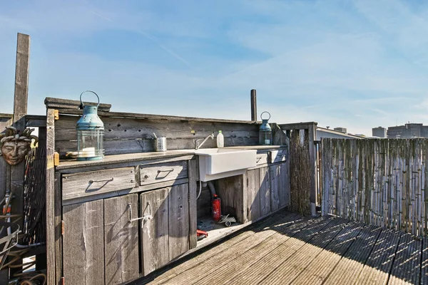 stock image Amsterdam, Netherlands - 10 April, 2021: an outdoor kitchen on a deck with blue sky and clouds in the photo is taken from inside, while its not visible