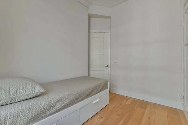 白い壁と木の床がある寝室部屋の隅に小さなベッドがあります — ストック写真
