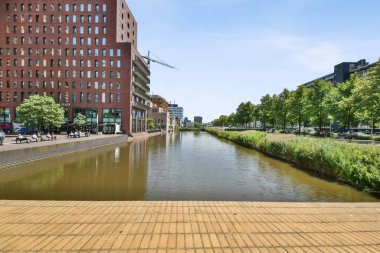 Amsterdam, Hollanda - 10 Nisan 2021: Sokakta arabaların park ettiği ve insanların kaldırımda yürüdüğü şehir merkezinin ortasındaki bir bina