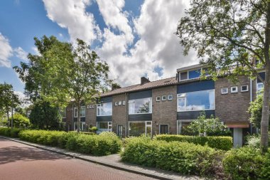 Hollanda 'da bir apartman kompleksi, sokağın her iki tarafında da ağaçlar ve çalılar var. Kırmızı tuğlalı bir yol var.