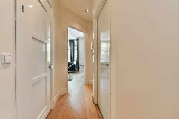 白い壁と木の床が両側にある長い廊下がリビングルームにつながり — ストック写真