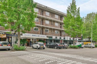 Birkaç araba yol kenarına park etmiş. Bir apartmanın önünde. Bir sürü pencere ve bant var.