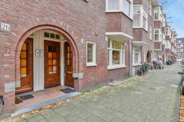 Amsterdam, Hollanda - 10 Nisan 2021: kaldırıma bisikletle park edilmiş tuğla bir bina ve arka planda yapraklarla kaplı bir daire