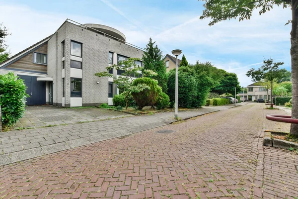 stock image Amsterdam, Netherlands - 10 April, 2021: an empty street in the middle of a residential area with trees and bushes on either side of the road there is a blue sky