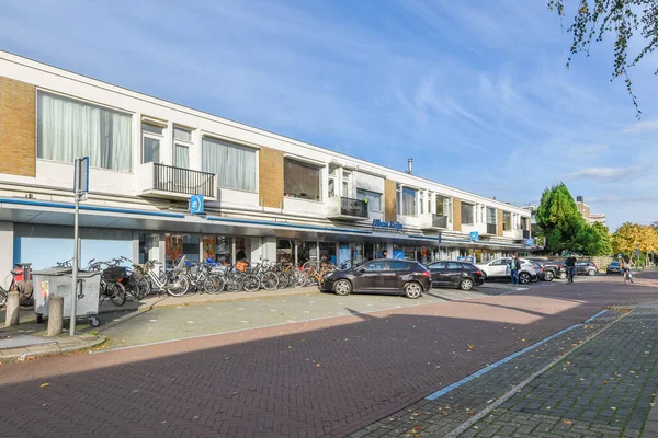 stock image Amsterdam, Netherlands - 10 April, 2021: a city street with parked cars and bicycles on the sidewalk in front of an apartment building that has been painted white