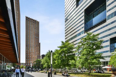 Amsterdam, Netherlands - 10 April, 2021: a building in the middle of an urban area with cars parked on the street and people walking down the sidewalk