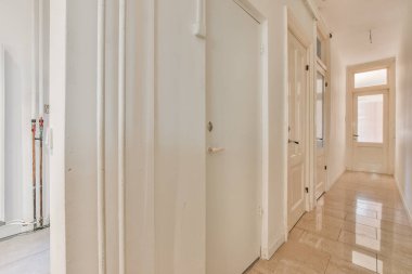 Beyaz duvarları ve kapı kolları olan boş bir koridor kimsenin olmadığı odaya ışık girmesi için kapalıdır.