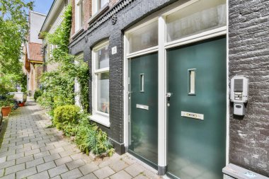 Amsterdam, Netherlands - 10 April, 2021: some cars parked on the side of a street in an urban area with bricked buildings and blue sky above