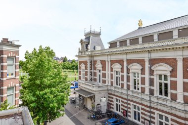 Amsterdam, Hollanda - 10 Nisan 2021: Önünde binalar ve ağaçlar olan bir dış alan - yatak odamın penceresinden alındı, ama ben...