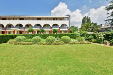 an empty park in the middle of a residential area, with trees and leaves scattered on the ground to the left