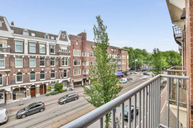 Amsterdam, Hollanda - 10 Nisan 2021: Sokakta arabaların park ettiği bir balkon ve arka planda binalar, Amsterdam, Hollanda - stokfoorent com
