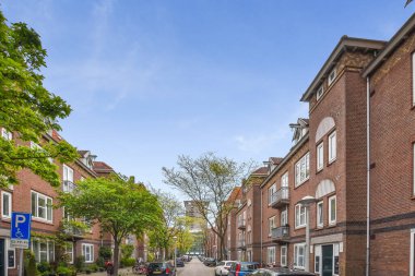 İki tarafında da arabaları olan bir şehir caddesi ve caddenin ortasında yürüyen insanlar.