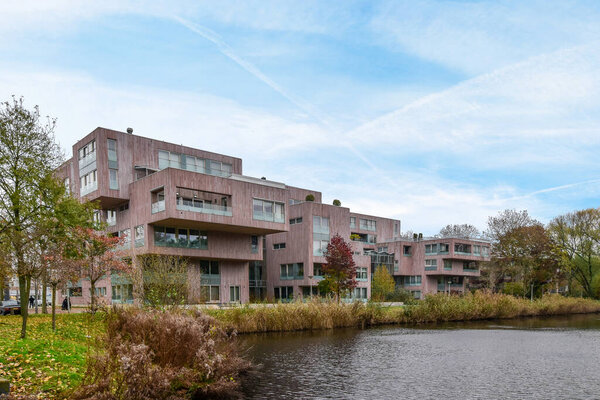 некоторые здания на стороне водоема с деревьями и кустами на переднем плане за ним