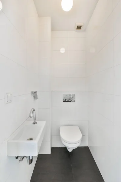 黒いタイル張りの床と角にトイレがある白いバスルーム壁に鏡があります — ストック写真