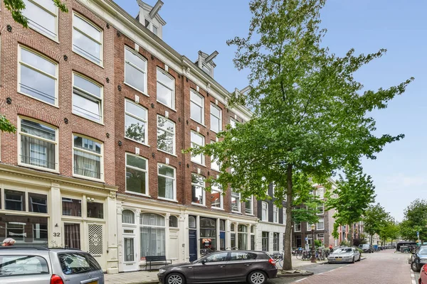 荷兰阿姆斯特丹 2021年4月10日 一些汽车停在街对面一排有门窗的砖楼前 — 图库照片