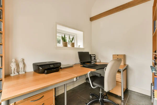 stock image Amsterdam, Netherlands - 10 April, 2021: a home office area with a desk, chair and printer on the right hand side of the room is empty