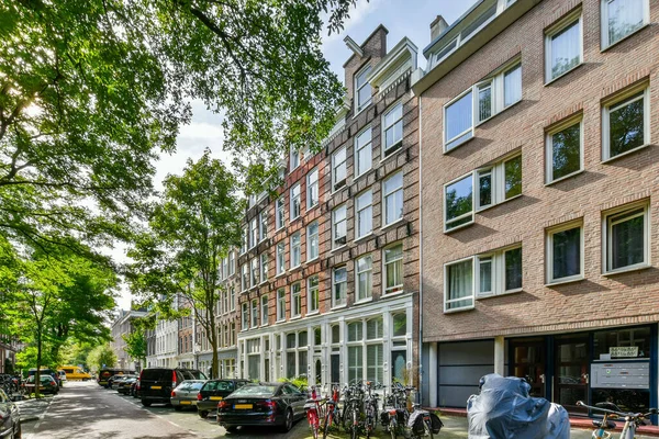 2021年4月10日 荷兰阿姆斯特丹 一条城市街道 在一些高耸的砖楼前面的路边停着汽车和自行车 — 图库照片