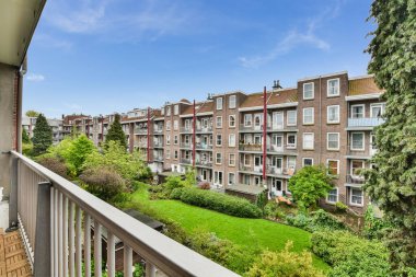 Ön planda yeşil çimenler ve ağaçlar olan bir apartman balkonu, Amsterdam, Hollanda stokfoorenlm