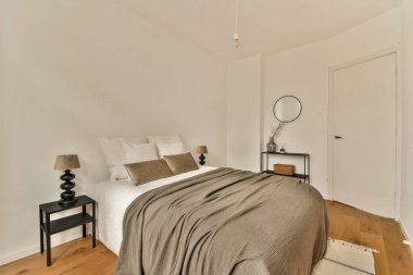 Yatak odası, komodin ve aynalar yatağın önünde beyaz bir kapı var.