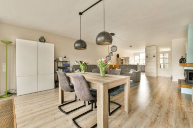 Ahşap döşemeleri, beyaz duvarları, açık renkli mobilyaları ve ahşap zemini olan bir evde mutfak ve yemek odası.