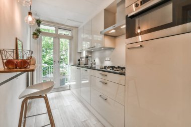 Odanın ortasında beyaz dolapları ve ahşap döşemeleri olan bir mutfak küçük bir verandaya açılan açık bir kapıdır.