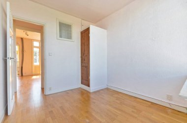 an empty room with wood flooring and white paint on the walls there is a door that leads to another room