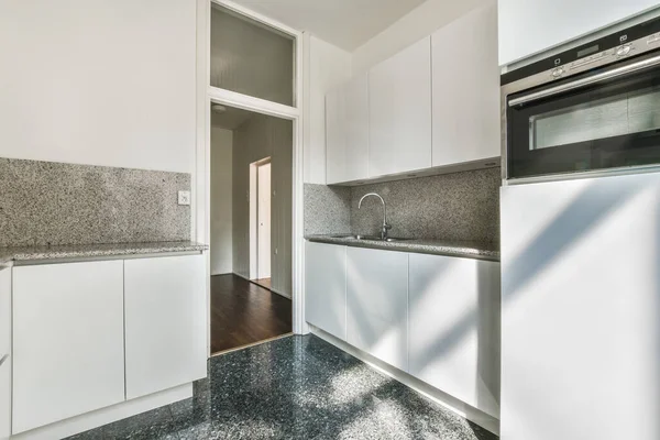 Beyaz Dolapları Siyah Granit Tezgahı Olan Bir Mutfak Kapısı Açık — Stok fotoğraf