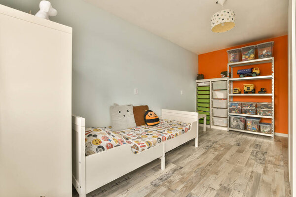 детская комната с оранжевым акцентом стены и белый шкаф кровать в углу комнаты