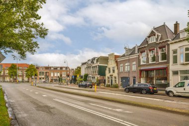 Amsterdam, Hollanda - 10 Nisan 2021: Kenarında arabalar ve arka planda evler olan bir şehir caddesi, gökyüzünde bazı binalar görülebilir.